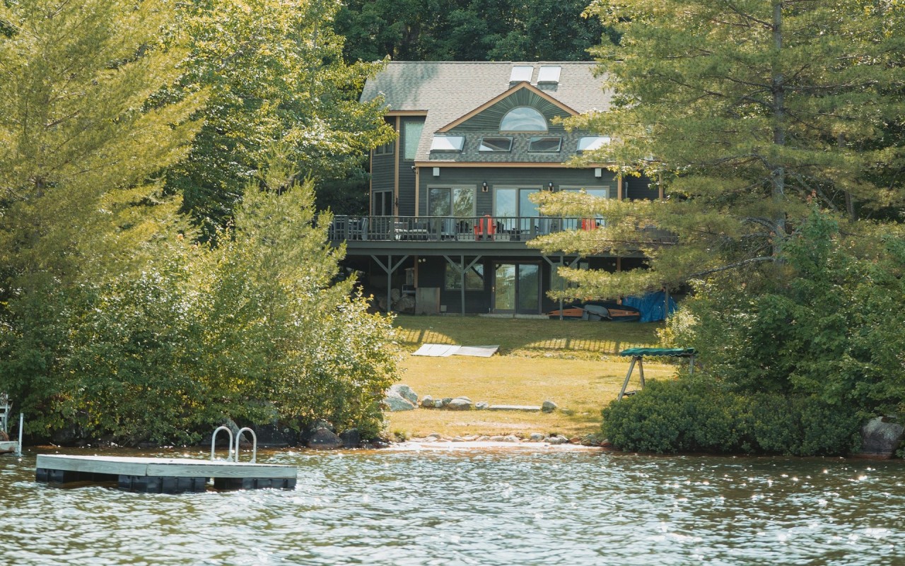 A lake house with a floating swim deck surrounded by greenery.